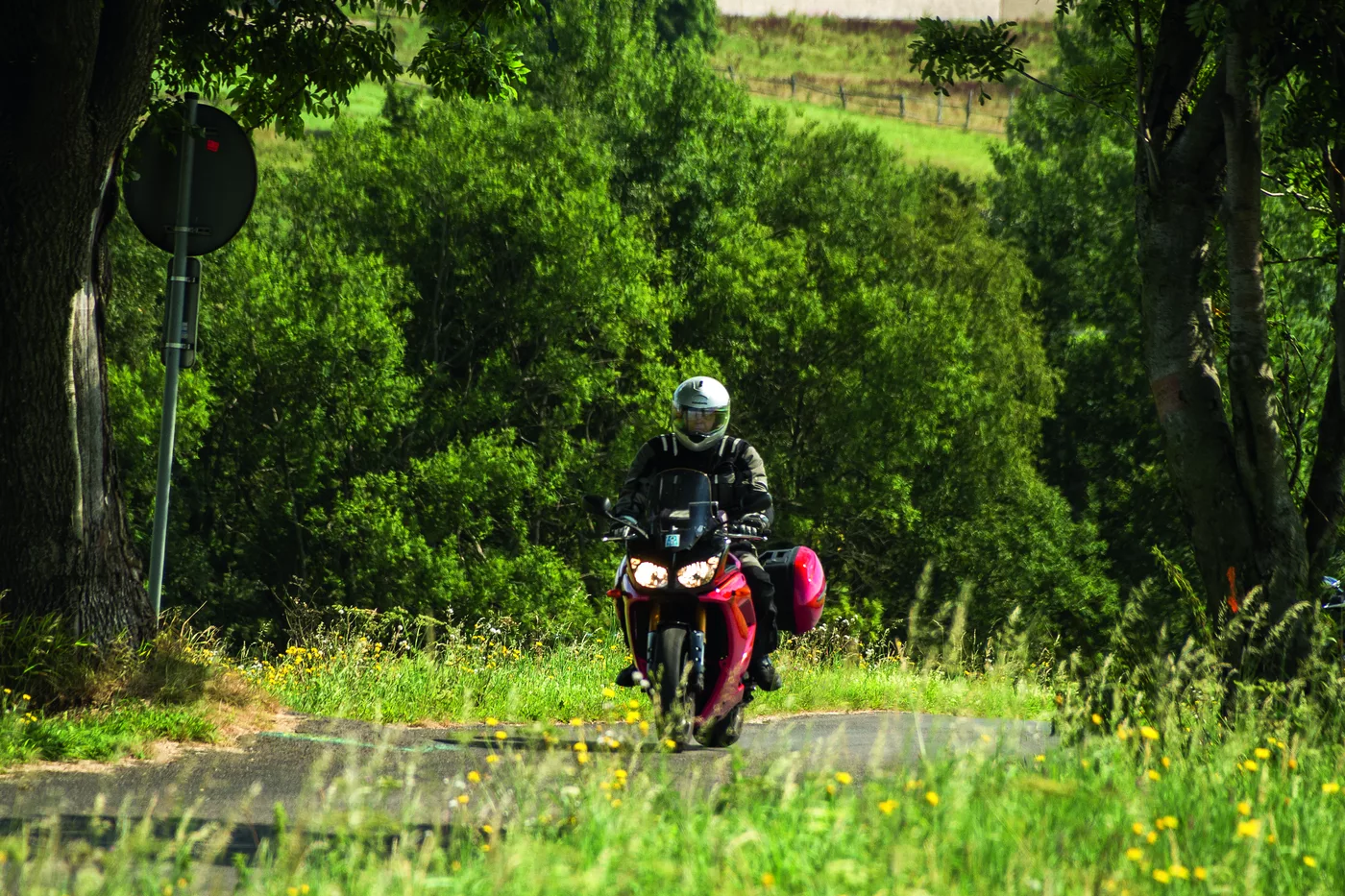 Motorrad auf einer schmalen Straße zwischen Wiesen und Büschen Motorrad auf einer schmalen Straße zwischen Wiesen und Büschen